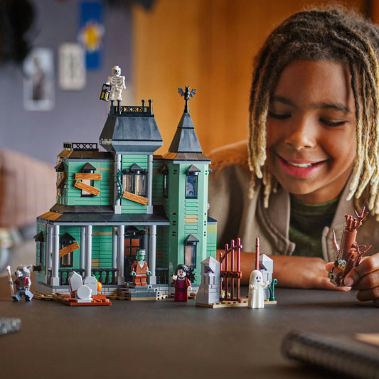 young oy smiling as he plays with a LEGO haunted house