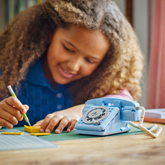 young girl playing with Blue LEGO retro telephone and pencil and notepad accessories