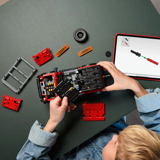 birds eye view of a young boy building red LEGO ford bronco