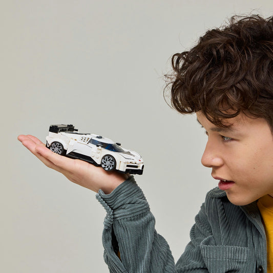 Young boy holding white LEGO car in the palm of his hand