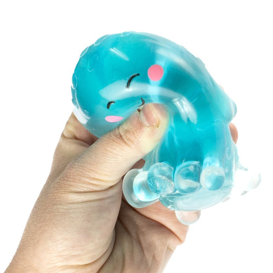Hand holding a blue jellyfish-shaped squishy toy with a smiling face on a white background