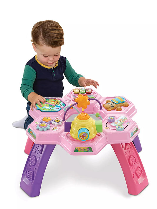 toddler playing with bright pink activity table on white background