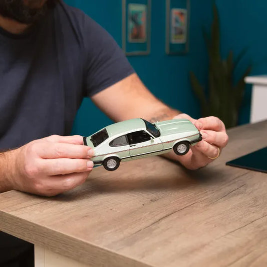 hands holding light green model car