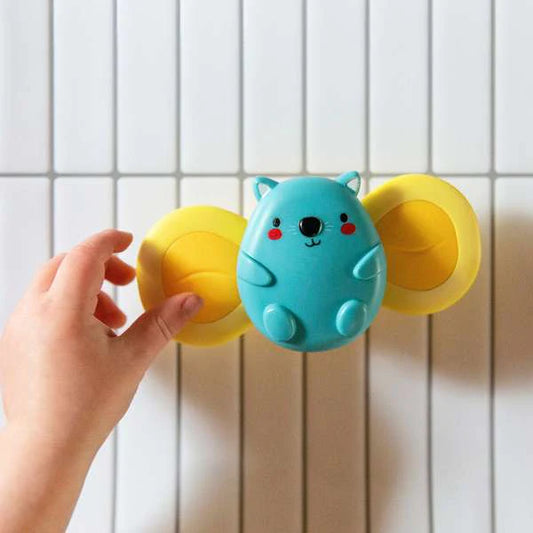 small hand reaching for blue and yellow sensory spinner on striped background