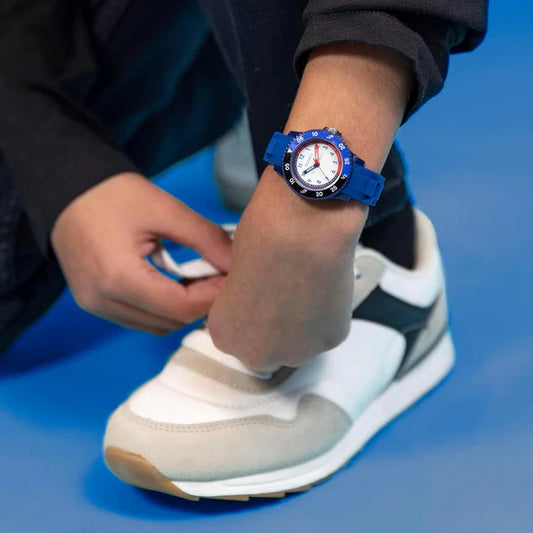 hand wearing time tikker blue watch while tying shoe