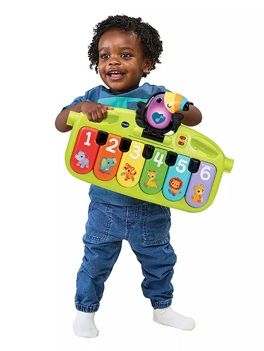 young toddler playing with bright green keyboard with black toucan bird attachment