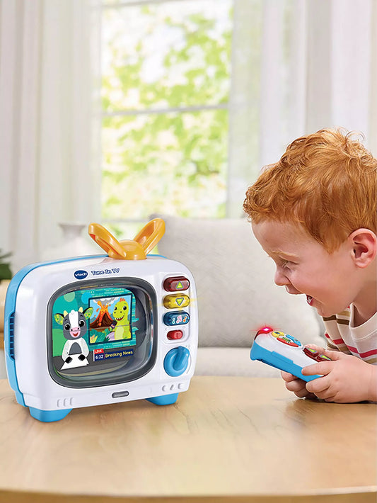 young boy playing with retro tv and remote in living room