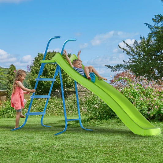 Two children playing on a green slide in a garden with a blue ladder.