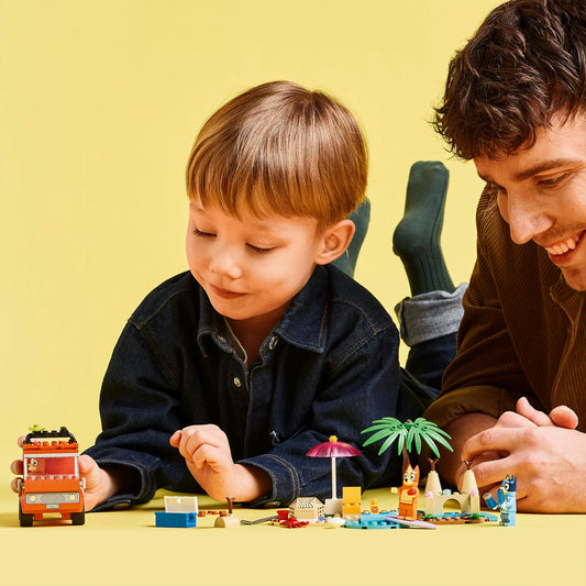 Young boy playing with lego car with adult on yellow backgound 