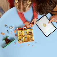 Bird's eye view of girl playing with lego house on a blue table 