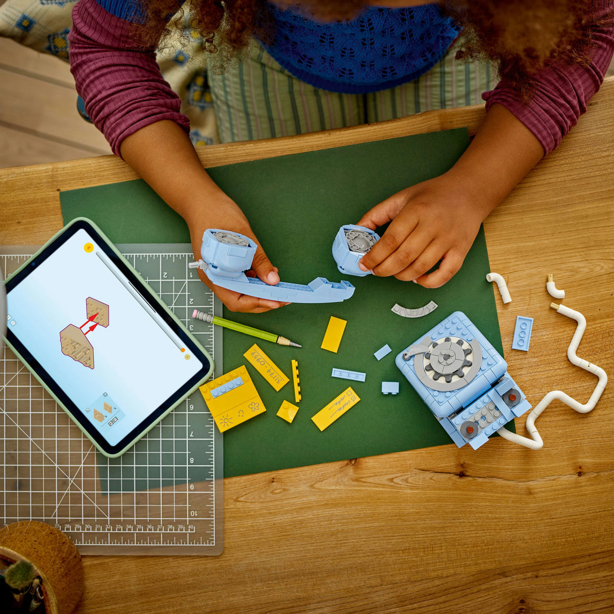 birds eye view of young girl building blue LEGO retro telephone and accessories 