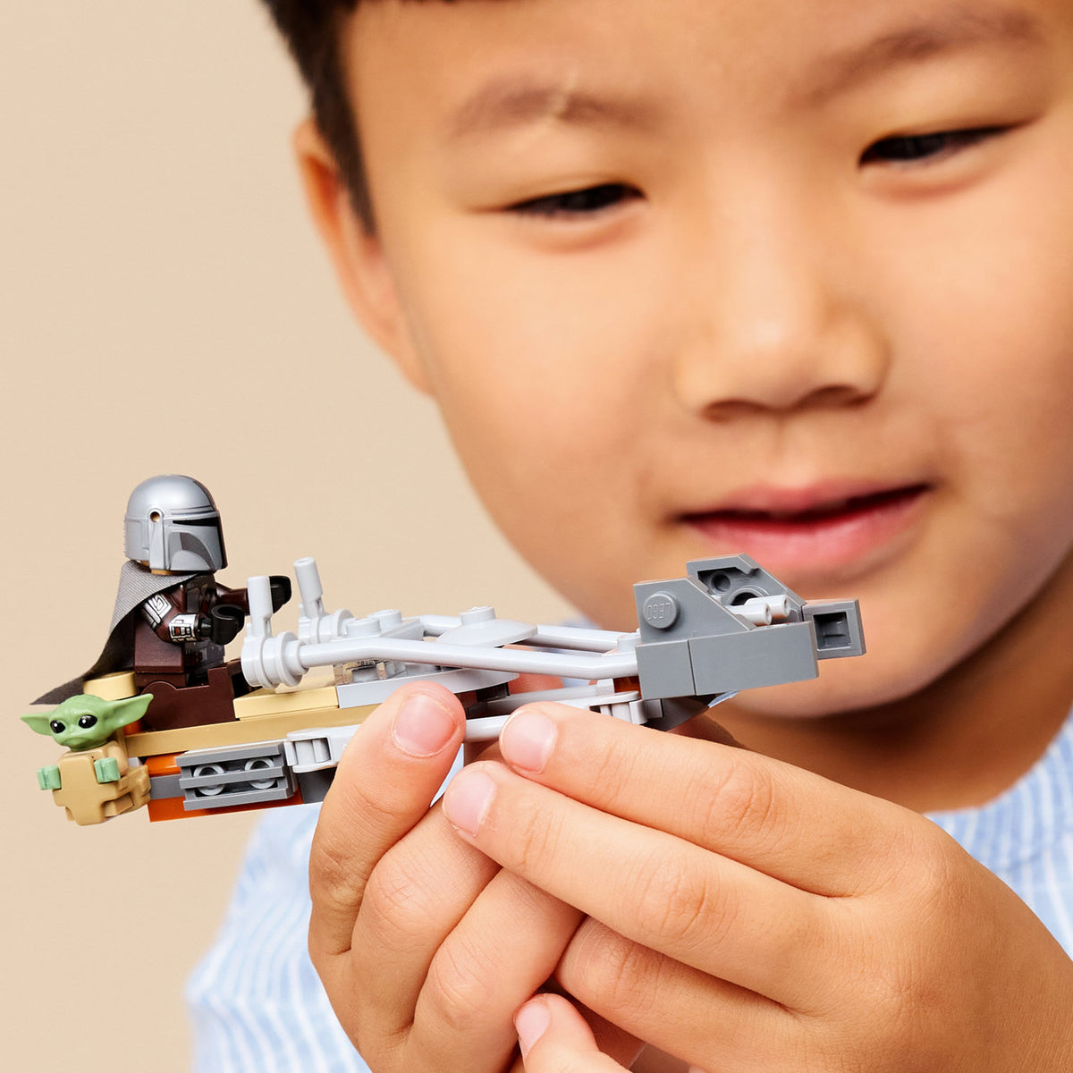 boy playing with lego star wars the mandalorian and grogus speeder bike 
