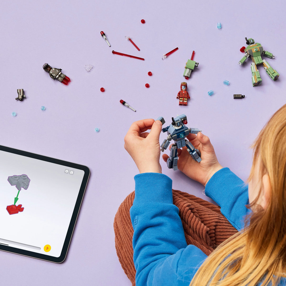 Birds eye view of young girl playing with LEGO action figure on purple background 