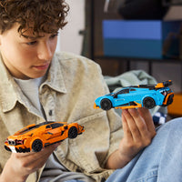 young boy holding two LEGO cars 