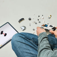 birds eye view of young boy building white LEGO car on white floor 