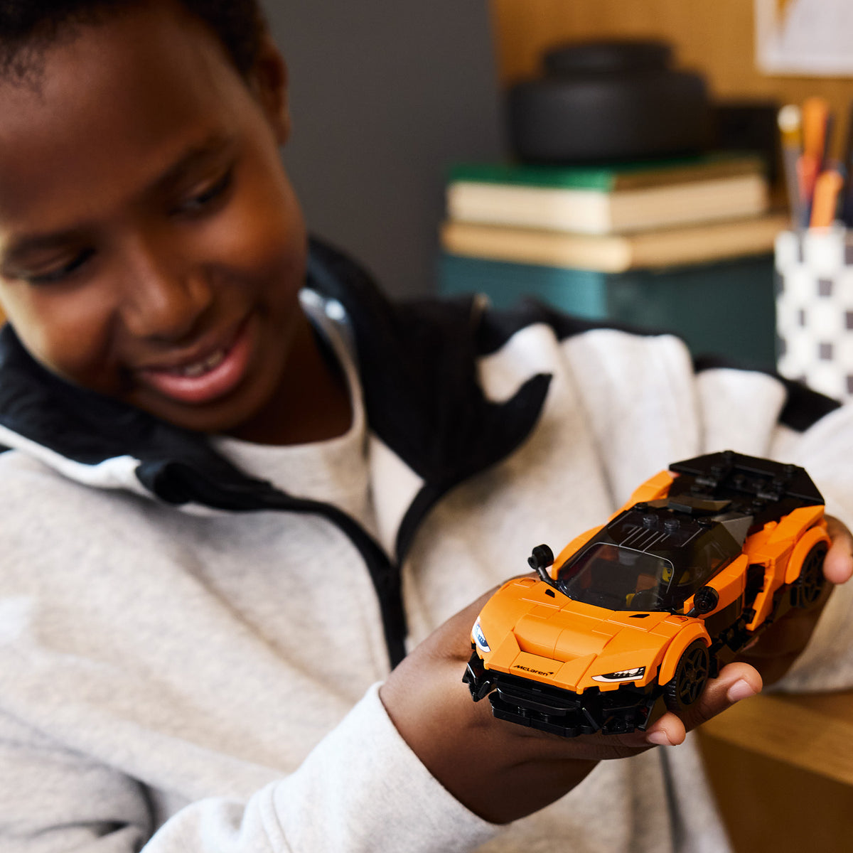 boy holding orange lego car 
