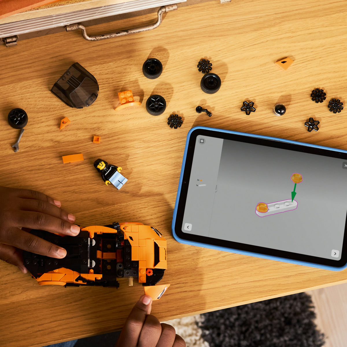 hands building orange lego car 