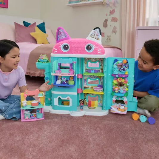 Two children playing with a colorful toy house in a bedroom.
