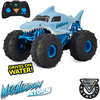 Toy vehicle resembling a megalodon with monster truck wheels and remote control, featuring Monster Jam branding.
