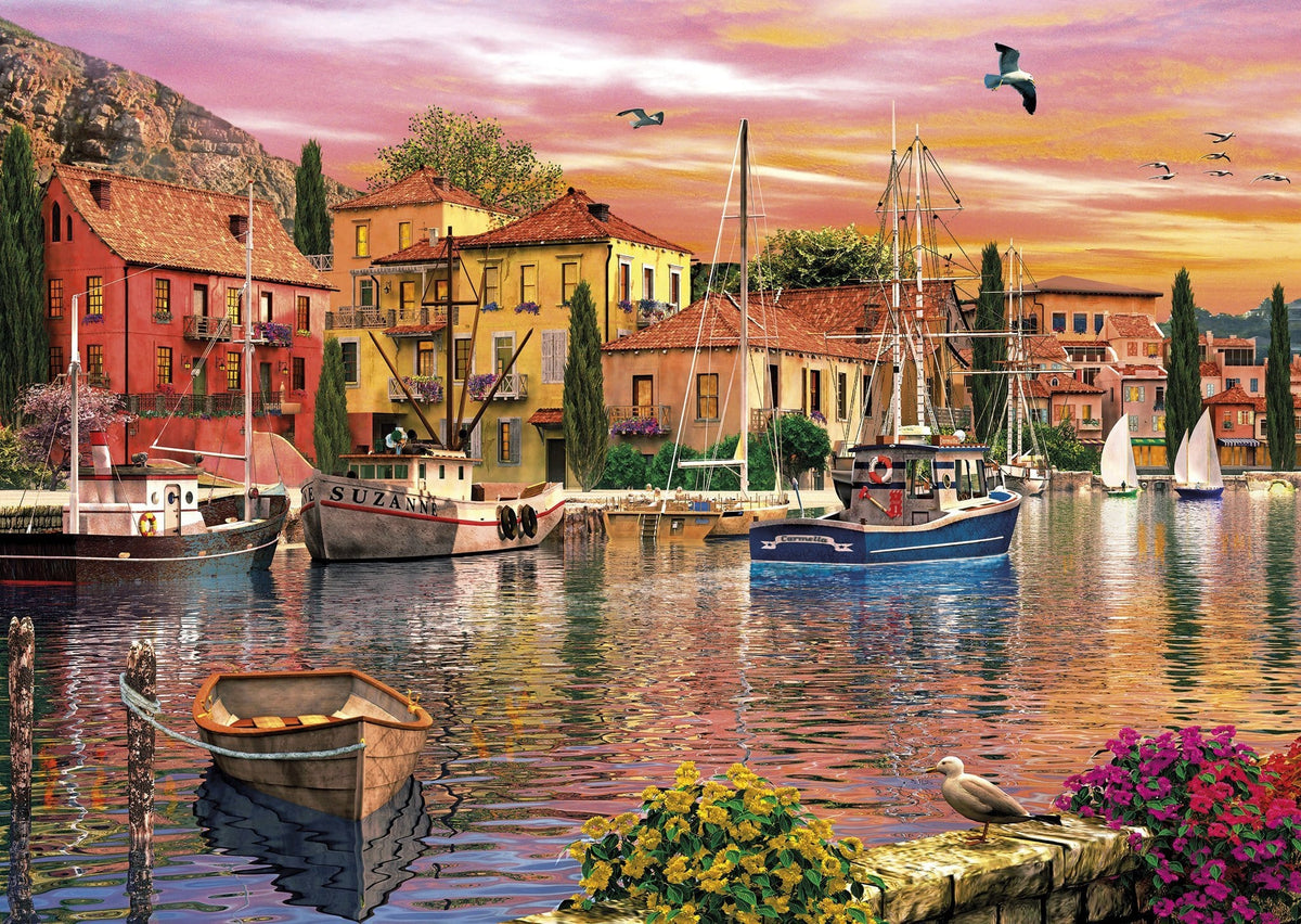 "Relaxing jigsaw puzzle set by Gibsons with sunset over the water and bobbing boats in serene colors."
