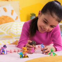 girl playing with dora figures on bed 