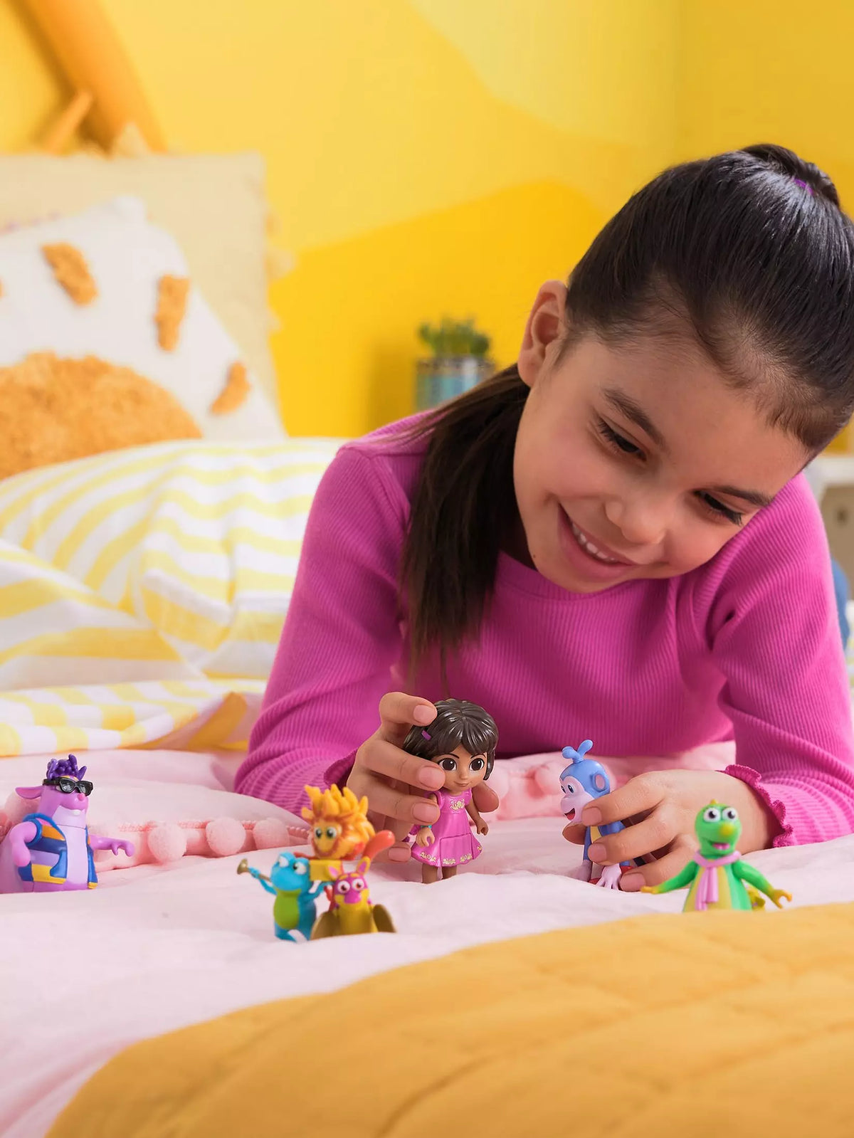 girl playing with dora figures on bed 