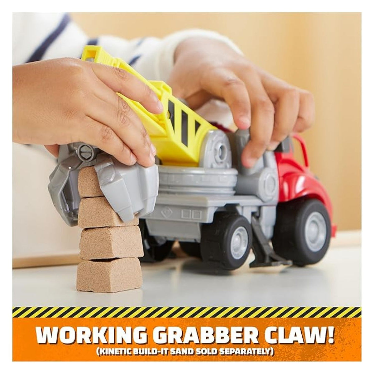 Child playing with the construction vehicle using the grabber claw to lift sand.