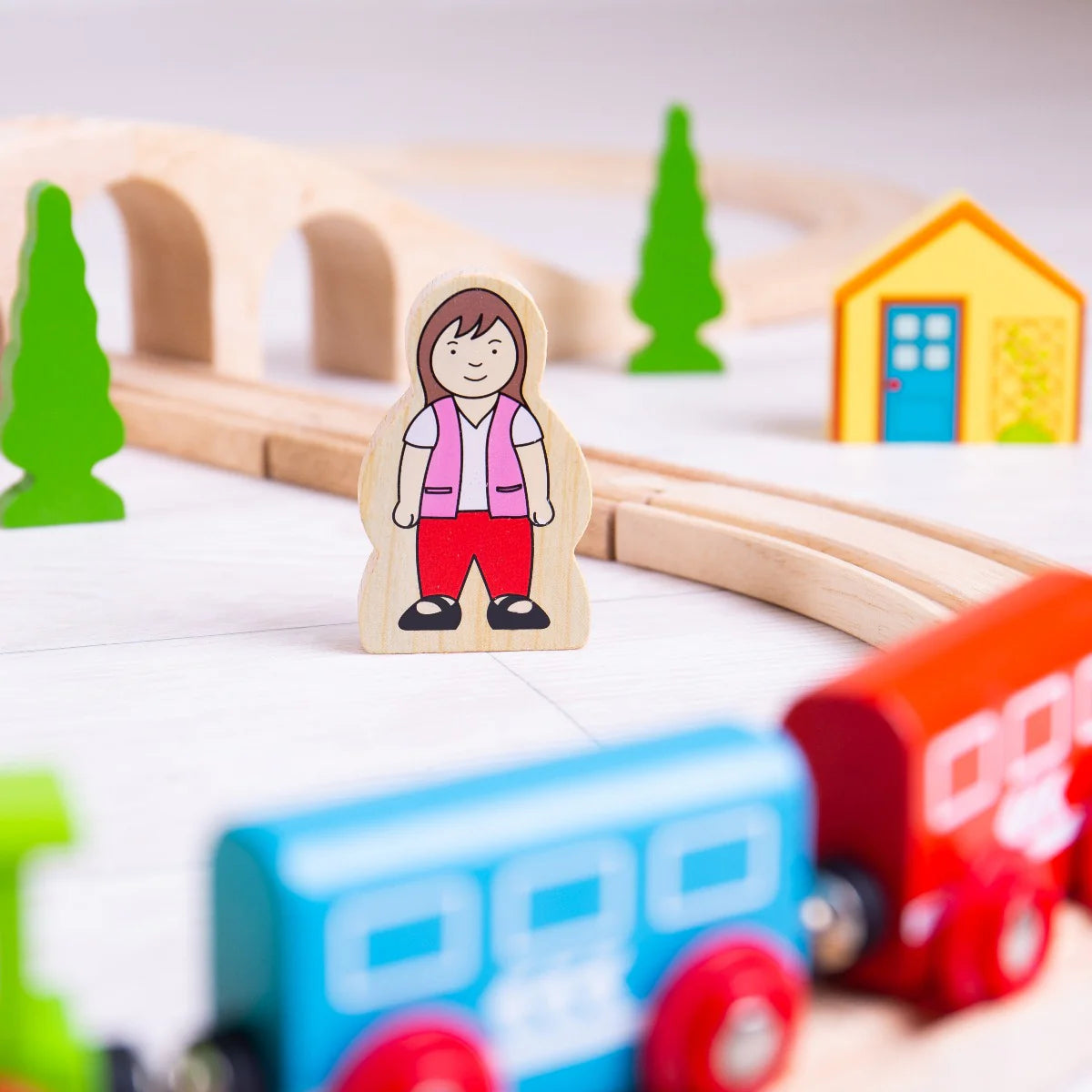 close up of wooden female character surrounded by wooden train and pieces 