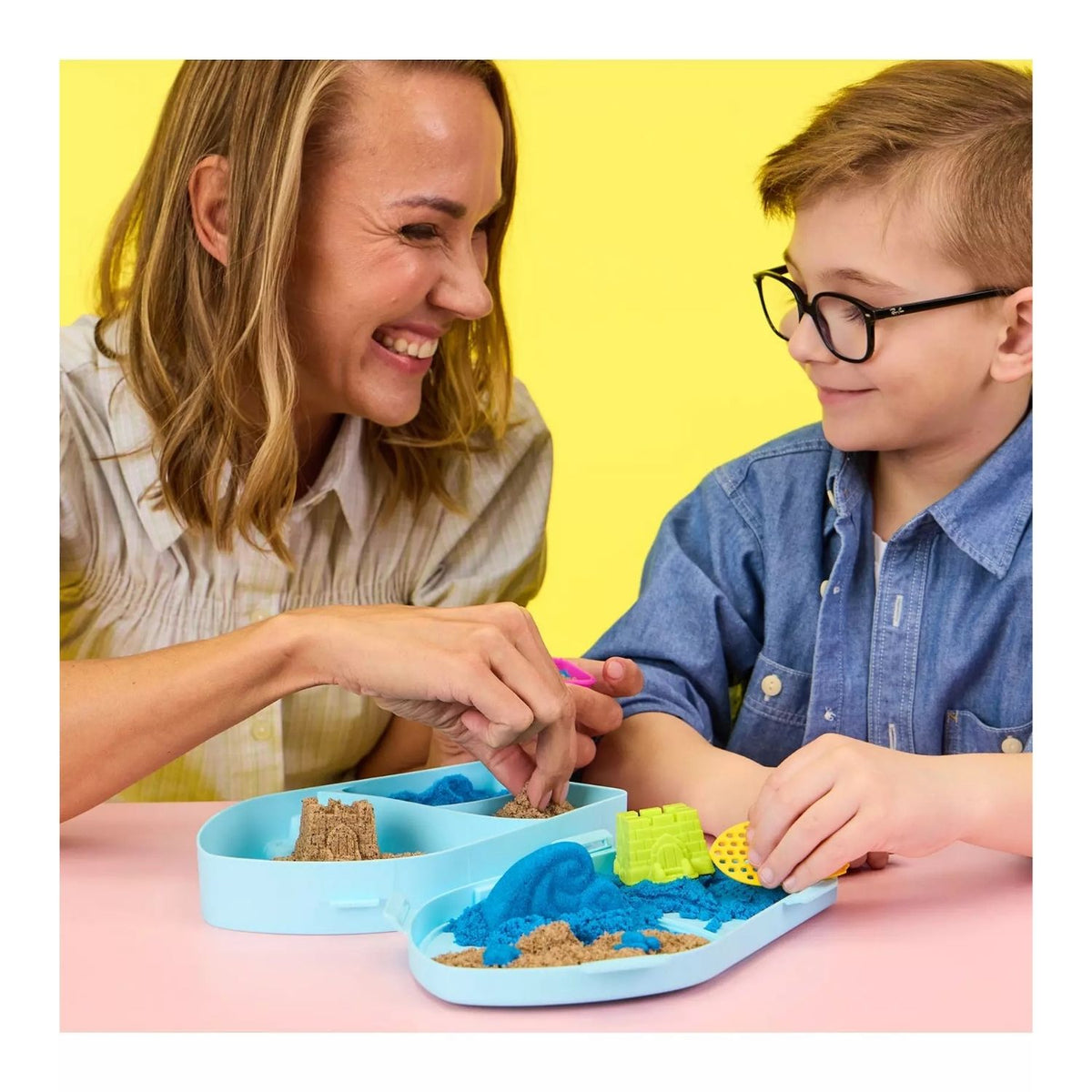 mother and son playing with kinetic sand at a table.