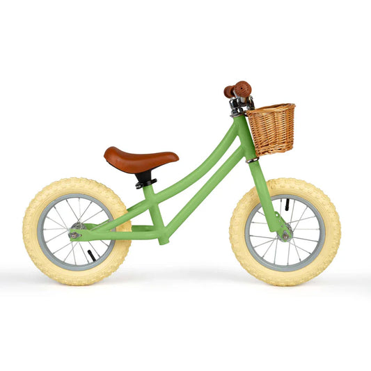Green balance bike with brown basket, seat and handles on white background