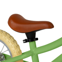 close up of Green balance bike with brown basket, seat and handles on white background
