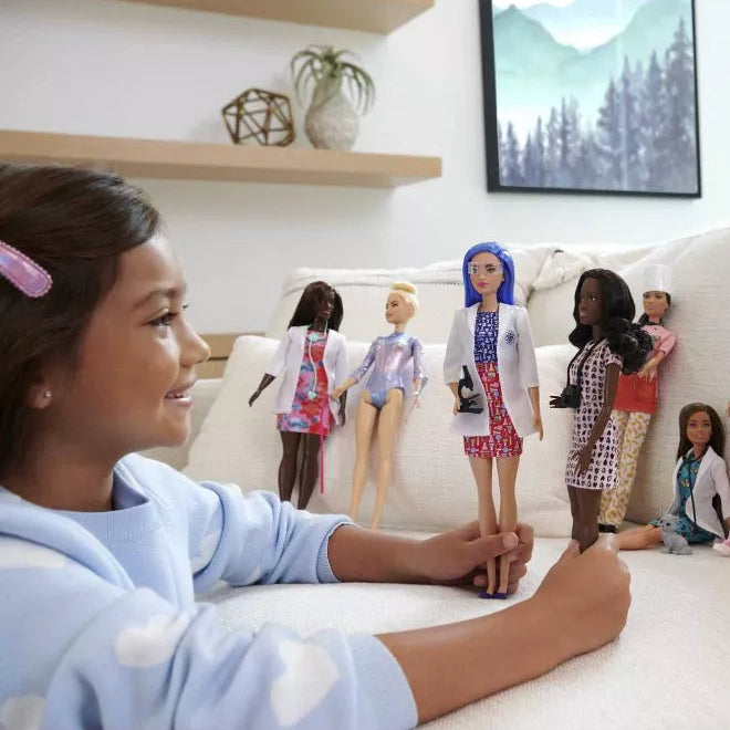girl playing with barbie career dolls 