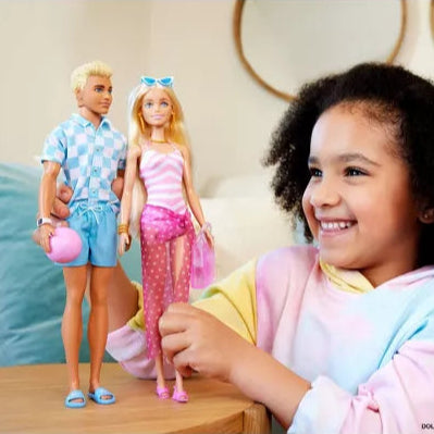 young girl playing with barbie and ken doll