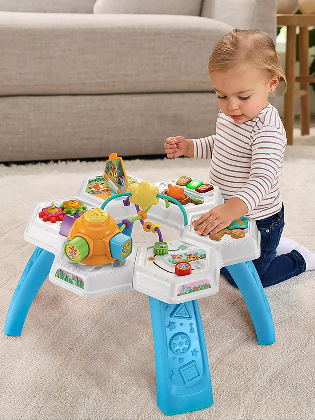 toddler playing with brightly coloured activity table 