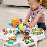 baby playing with top of activity table 