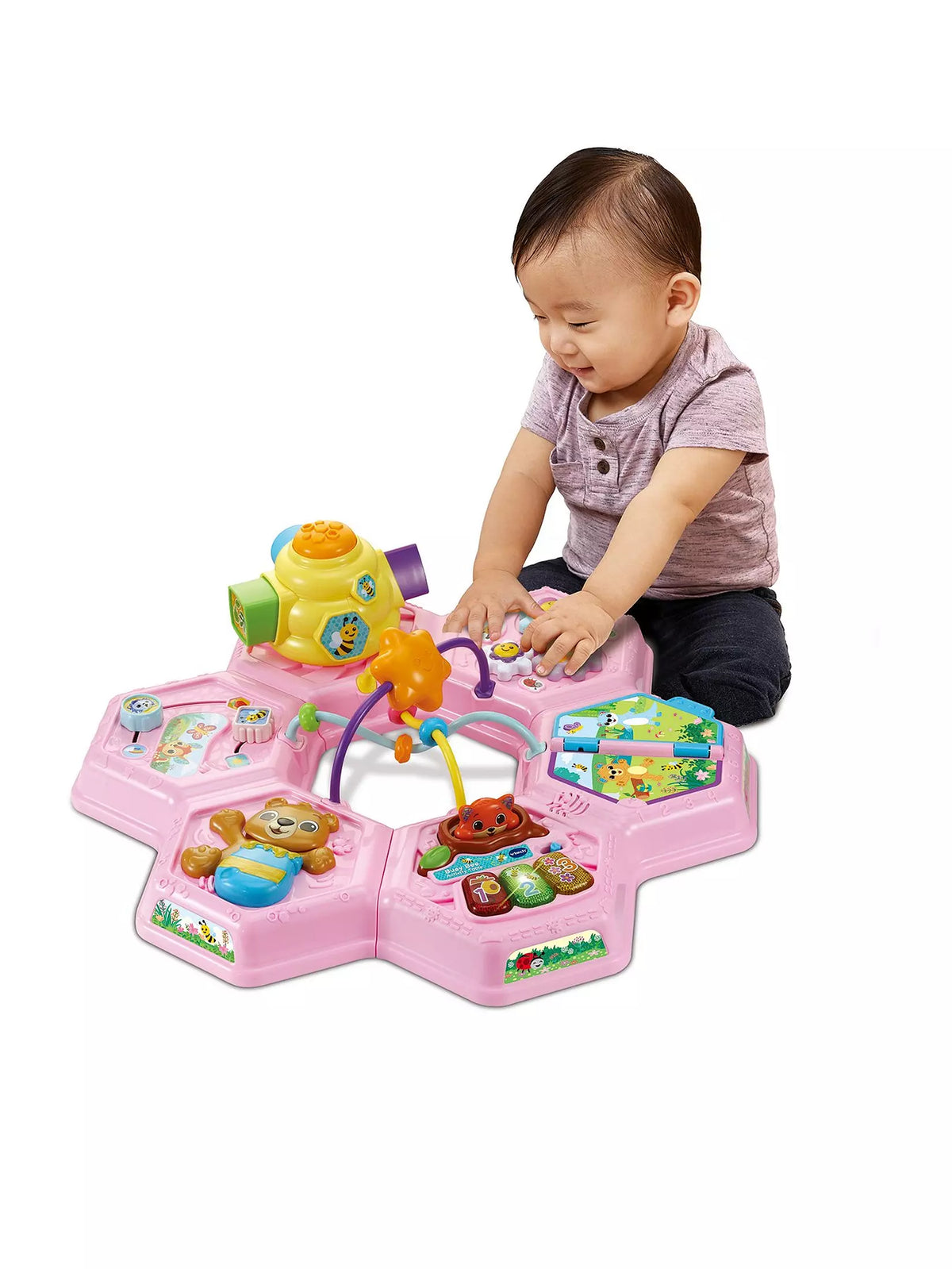 baby playing with top of pink activity table on white background 