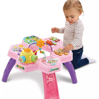 toddler kneeling playing with bright pink activity table on white background 
