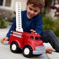 boy playing outside with fire truck 