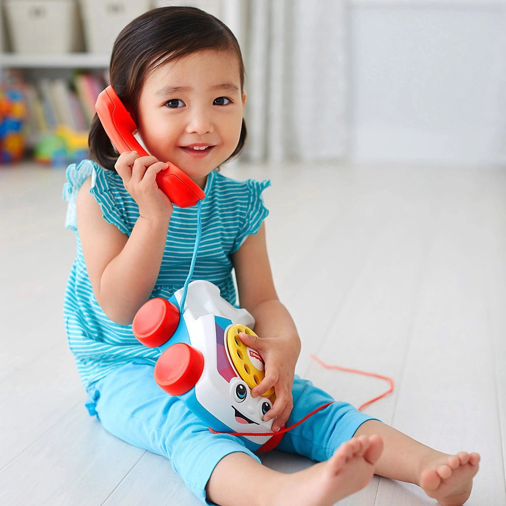young girl playing with colourful children's rotary phone on white background