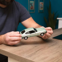hands holding light green model car 