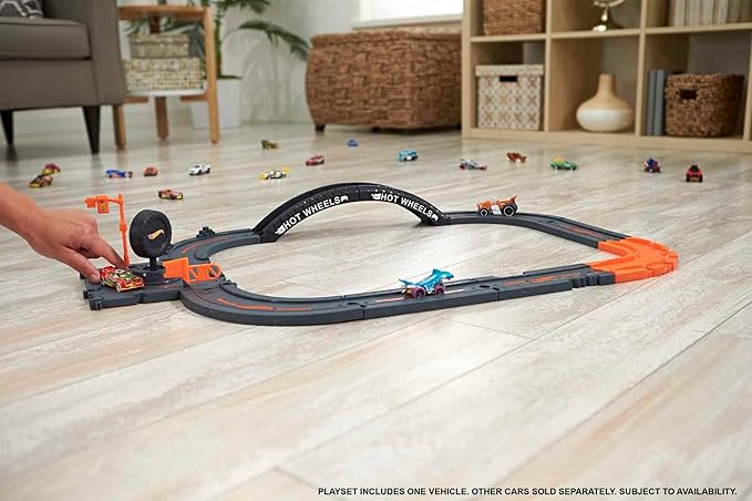 hot wheels city track on wooden floor with small child playing with it  