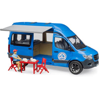 figurine sitting at a table beside campervan 