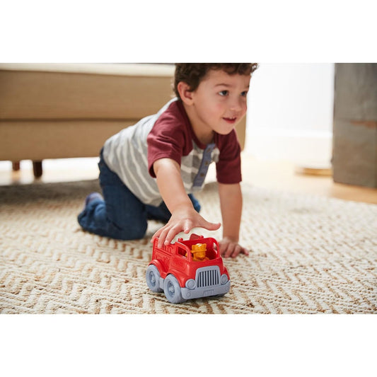boy playing on carpet with mini fire truck 