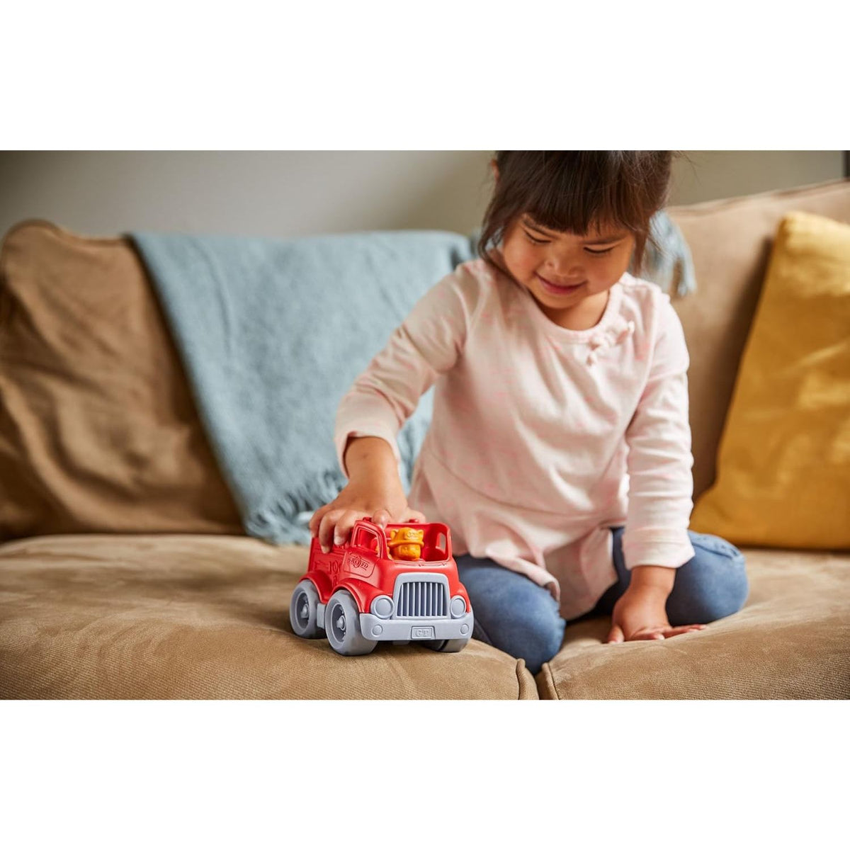 girl playing on couch with mini fire truck 