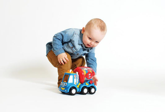 baby playing with toy cement mixer on  a white background