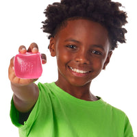 young boy holding out pink squishy cube 