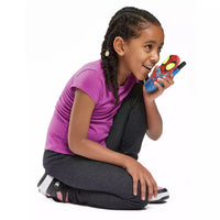 young girl holding a blue spider man walkie talk and smiling on a white background