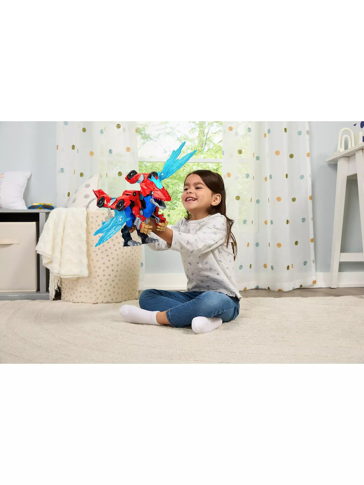 young girl in bedroom playing with red dinosaur with blue wings 