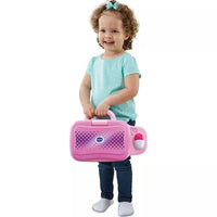 toddler standing holding pink toy laptop on white background 