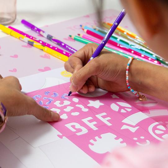 girl using stencil to colour in top model colouring book 